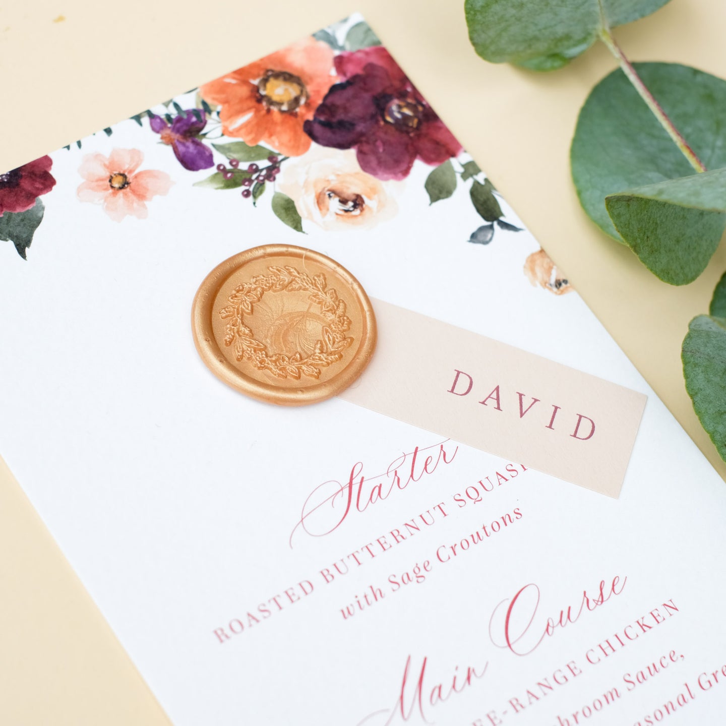 wedding menu with autumnal flowers in burgundy, burnt orange and earthy neutrals personalised with guest name and wax seal